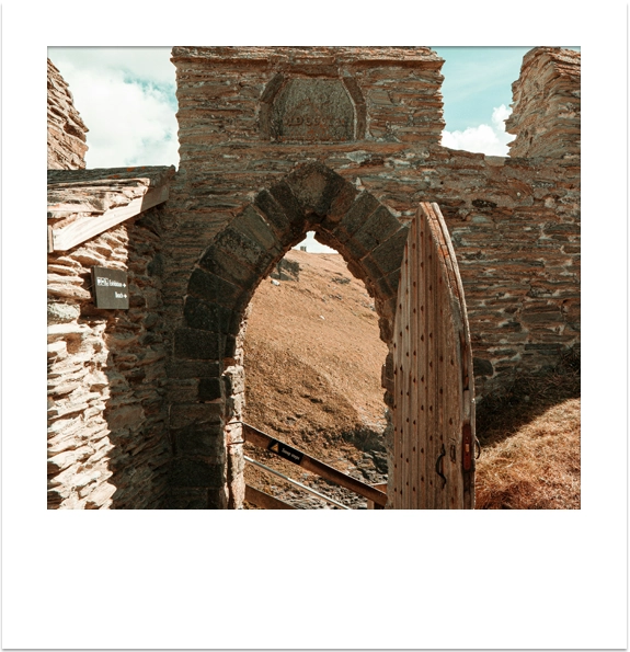 Historic stone archway and wooden door at Tintagel Castle ruins.
